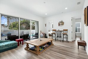 A spacious living area with a large sliding glass door leading to a balcony, a wooden dining table, and a cozy seating arrangement. - Grand Vilano Compound: 18 Guests, 2 Pools (St. Augustine)