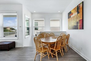 A dining area with a round table and wooden chairs, white walls, and a large window with blinds. - Grand Vilano Compound: 18 Guests, 2 Pools (St. Augustine)