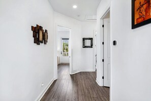 A hallway with a wooden floor, white walls, and a door leading to another room. - Grand Vilano Compound: 18 Guests, 2 Pools (St. Augustine)