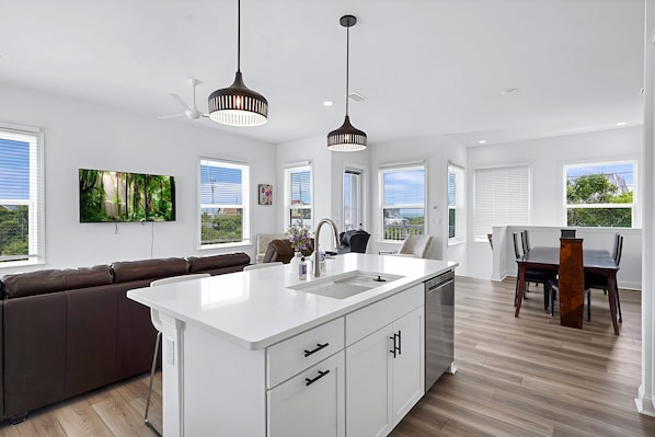 A modern kitchen with a central island, white cabinetry, and a dining area with a table and chairs. - Grand Vilano Compound: 18 Guests, 2 Pools (St. Augustine)