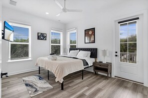 A bedroom with a bed, bedside tables, a ceiling fan, and large windows. - Grand Vilano Compound: 18 Guests, 2 Pools (St. Augustine)