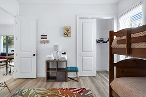 A bedroom with a bunk bed, a bedside table with a lamp, a chair, and a small shelf with folded towels. - Grand Vilano Compound: 18 Guests, 2 Pools (St. Augustine)