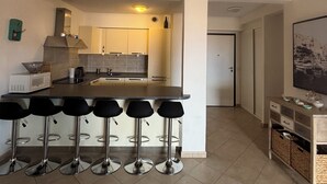Et moderne køkken med en central ø, barstole og en mikrobølgeovn.