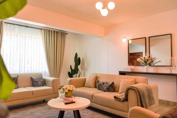 Un salon comprenant un canapé, une table basse, une grande plante et un miroir au mur.
