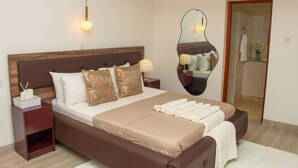 Une chambre à coucher avec un grand lit, une table de chevet avec une lampe, un miroir et une tête de lit en bois.