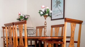 Une table à manger avec des chaises, un vase rempli de fleurs, un tableau encadré accroché au mur et une lampe.
