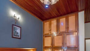 Une chambre à coucher avec une tête de lit en bois, un lit recouvert d’une literie à motifs, une lampe fixée au mur et une armoire en bois.
