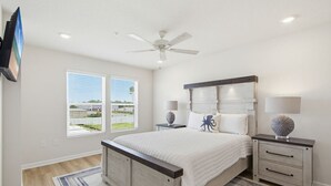 A bedroom with a bed, nightstands, a ceiling fan, and a TV mounted on the wall. - Lost Bay Hideaway | Garden View (Orange Beach)