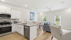 A modern kitchen with white cabinets, a built-in oven, and a dishwasher. - Lost Bay Hideaway | Garden View (Orange Beach)