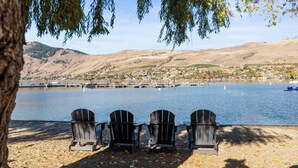 Three Adirondack chairs on a lakeside dock with a view of a town across the water. - Welcome to Lakeside Lookout – your easy, lakeside, Okanagan getaway. (Vernon)