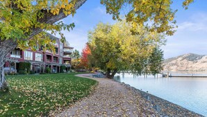 A multi-story building with a landscaped lawn and a lake view. - Welcome to Lakeside Lookout – your easy, lakeside, Okanagan getaway. (Vernon)