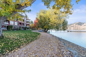 A multi-story building with a landscaped lawn and a lake view. - Welcome to Lakeside Lookout – your easy, lakeside, Okanagan getaway. (Vernon)