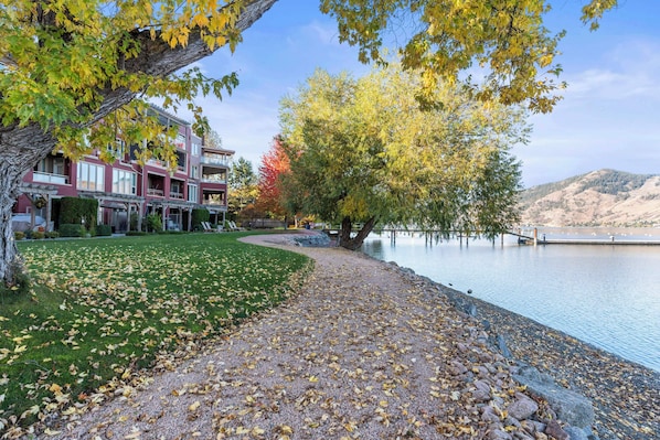 A multi-story building with a landscaped lawn and a lake view.