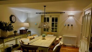 Ein Esszimmer mit Holztisch, Stühlen, einer Pendelleuchte, einer Uhr und einer Heizung.