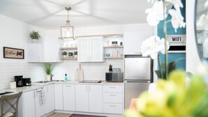 A modern kitchen with white cabinets, a stainless steel refrigerator, a coffee maker, and a 'grateful' doormat. - Ocean View! Jacuzzi! Outdoor Living! Centrally Located! (Arecibo)