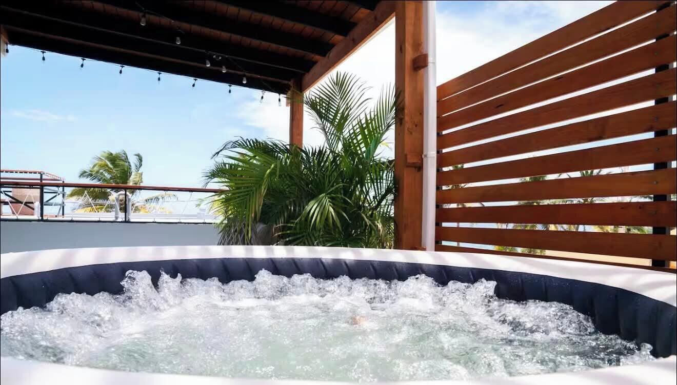 A hot tub with water jets, surrounded by wooden slats and palm trees.