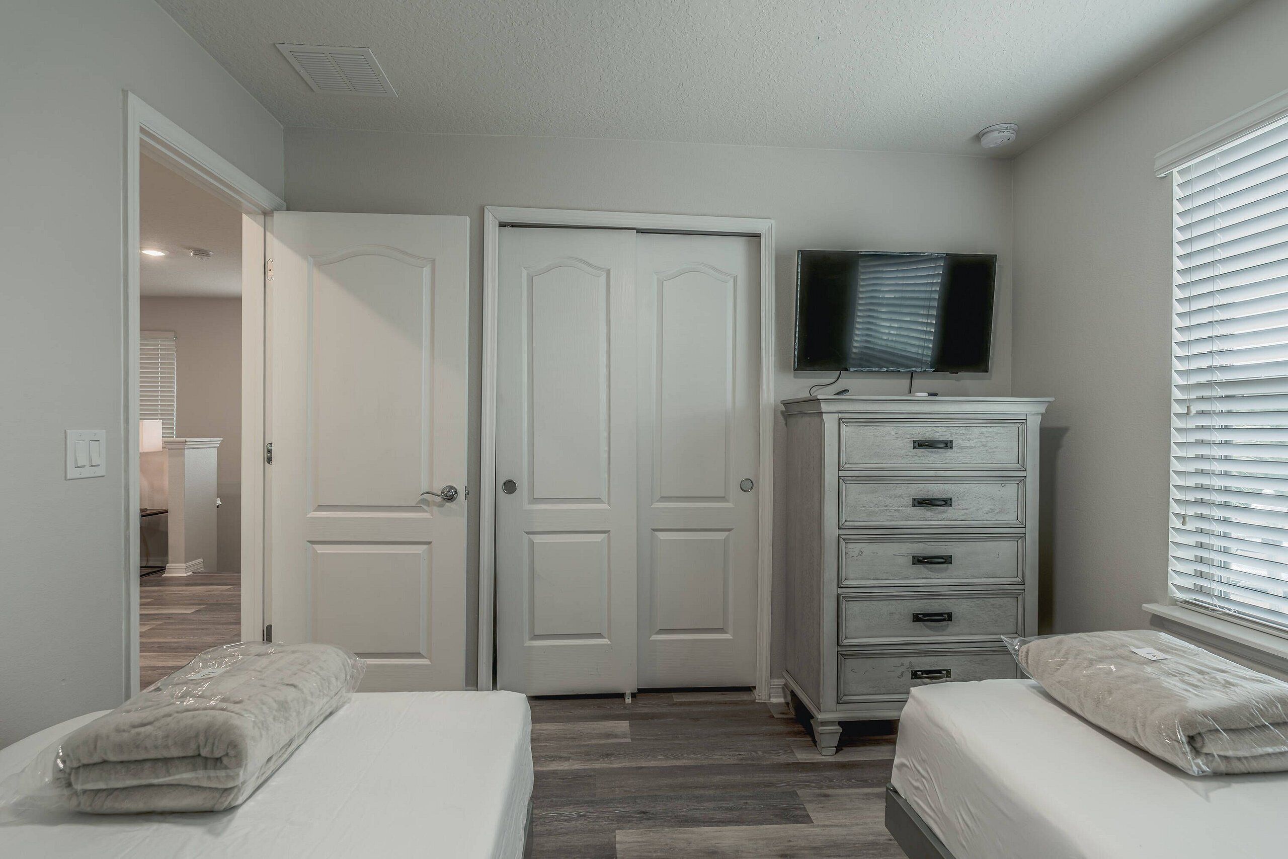 Une chambre avec deux lits, une commode, un téléviseur et un placard.