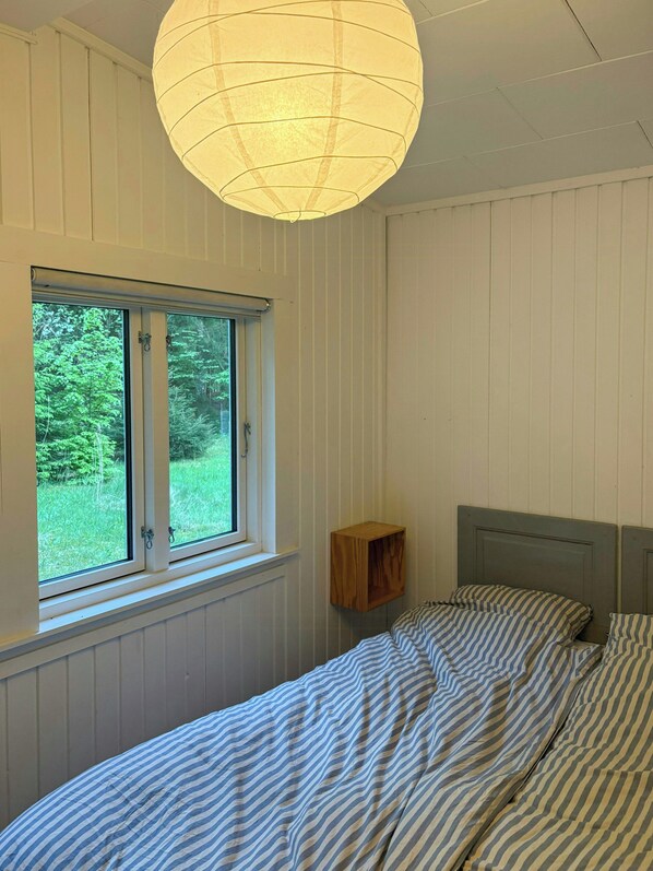 Un dormitorio con cama, ventana y lámpara colgante.