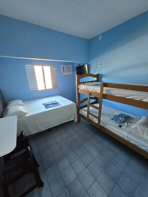 Ein Zimmer mit zwei Etagenbetten, einem Schreibtisch, einem Stuhl, einem Fenster mit Jalousien und einer Klimaanlage.