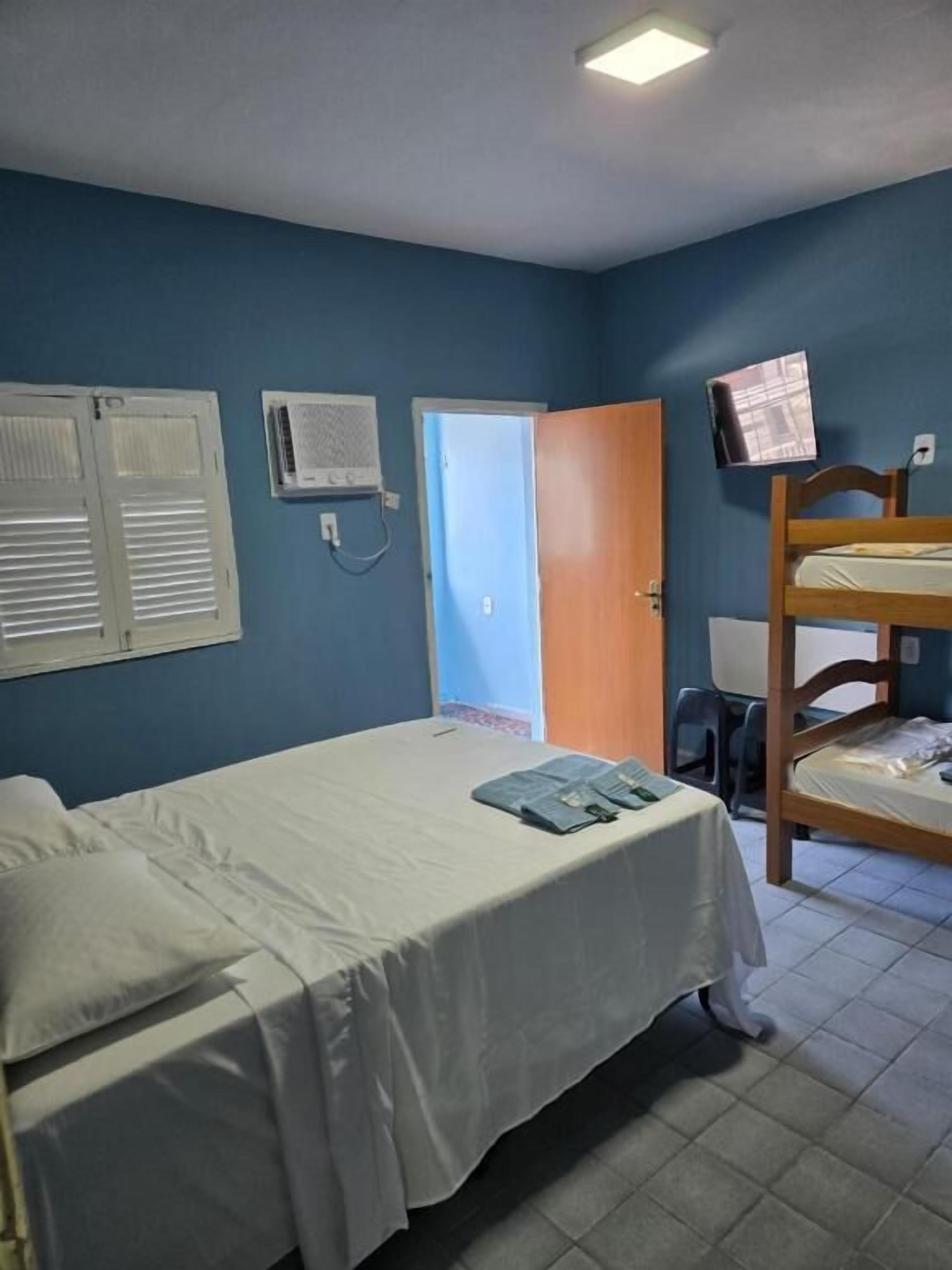 Ein Zimmer mit einem Bett, einem Etagenbett, einer Tür und einer Wand-Klimaanlage.