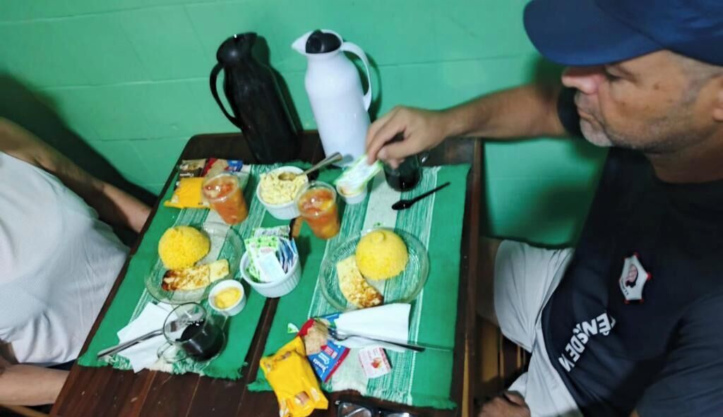 Uma mesa de jantar com comida, um jarro e uma pessoa usando boné.