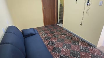 Una habitación con sofá, puerta, escalera y televisor montado en la pared.