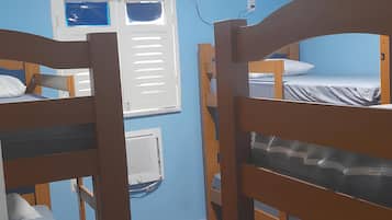 Un dormitorio con literas, ventilador de techo, ventana y calentador en la pared.
