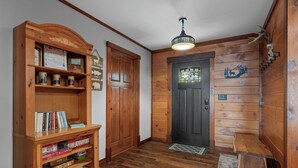 A wooden interior with a bookshelf, a door, and a ceiling light fixture.