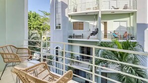 A multi-story building with balconies, wicker chairs, and potted plants.