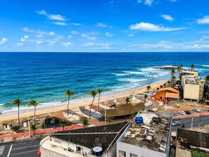 Blick auf eine Küstenlandschaft mit Strand, Palmen und Gebäuden.