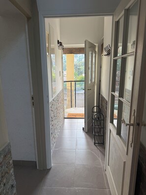 Ein Flur, der zu einem Balkon mit Blick auf ein Gebäude und Bäume führt.