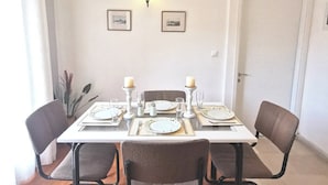 Ein Essbereich mit einem Tisch für vier Personen, Stühlen, einer Wandleuchte und gerahmten Bildern.