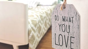 Ein Schlafzimmer mit Bett, einer Tür inklusive Türgriff und einem motivierenden Spruch.