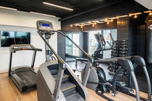 Un gimnasio con cintas de correr, elípticas y equipo de pesas.