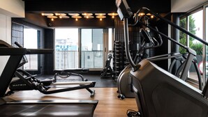 Ein Fitnessstudio mit Laufbändern, Rudergerät und einer Gewichtshalterung.