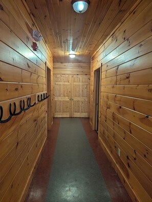 A wooden hallway with a green carpet, wooden walls, and a door at the end.