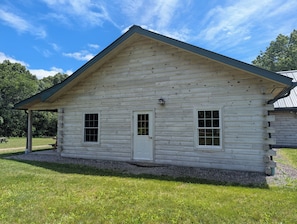 A log cabin with a gabled roof, a front door, and two windows.