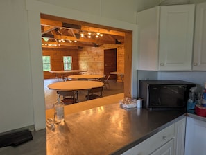 A modern kitchen with a microwave, cabinets, and a dining area with tables and chairs.