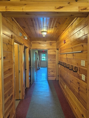 A wooden hallway with doors, a light fixture, and a wall-mounted coat rack.