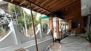 An outdoor seating area with a wooden ceiling, green artificial grass, and white furniture. - Hostal Brisas Del Mar  (Puerto Villamil)