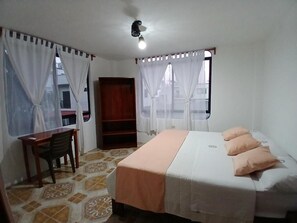 A bedroom with a bed, a desk, and a chair. - Hostal Brisas Del Mar  (Puerto Villamil)