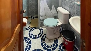 A bathroom with a toilet, sink, shower, and patterned floor tiles. - Hostal Brisas Del Mar  (Puerto Villamil)