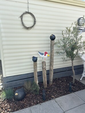 A decorative bird sculpture with a red beak and blue wings, mounted on a wooden post. - Kamperland Beach Home for 4 Guests (Kamperland)