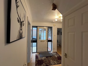 A hallway with a door, a patterned rug, and a framed picture on the wall. - Spacious Family Residence with large south facing gardens close to Eden Project (St Austell)
