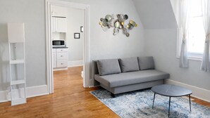 Ein modernes Wohnzimmer mit einem grauen Sofa, einem kleinen runden Tisch und einer Wanddekoration.