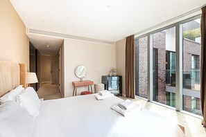 Ein Hotelzimmer mit einem großen Bett, einem Nachttisch mit Spiegel, einem Schminktisch und Blick ins Freie.
