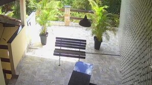Eine Terrasse mit einer Bank, Topfpflanzen und einem Fliesenboden.
