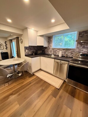 A modern kitchen with white cabinets, a stainless steel dishwasher, and a black oven. - Bright Walk-Out Suite with Private Entrance, Parking & Backyard … (Aurora)