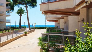Un hotel a la costa amb balcons, un camí pavimentat i vista al mar.