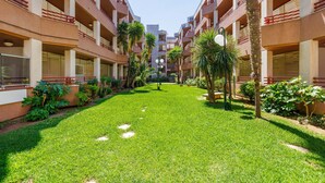 Un pati interior amb un jardí central, envoltat d'edificis de diverses plantes amb balcons i finestres.